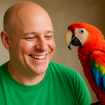 a bald headed man in a green t shirt smiling at a parrot