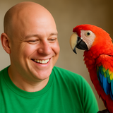 a bald headed man in a green t shirt smiling at a parrot